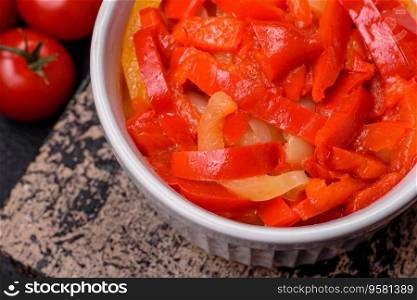 Delicious fresh saute sweet bell pepper slices with onion, salt, spices and herbs on a dark concrete background