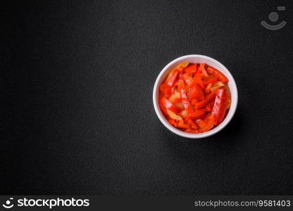 Delicious fresh saute sweet bell pepper slices with onion, salt, spices and herbs on a dark concrete background