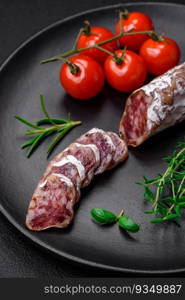 Delicious fresh smoked fuet sausage with salt, spices and herbs on a dark concrete background