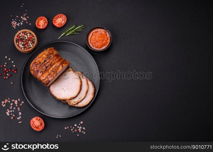 Delicious fresh smoked meat or ham with spices and herbs on a dark concrete background