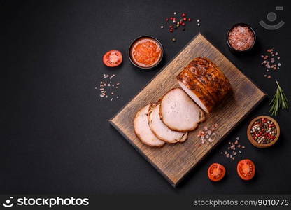 Delicious fresh smoked meat or ham with spices and herbs on a dark concrete background