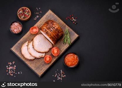 Delicious fresh smoked meat or ham with spices and herbs on a dark concrete background