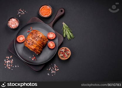 Delicious fresh smoked meat or ham with spices and herbs on a dark concrete background