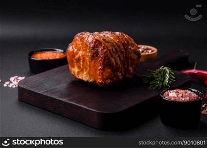 Delicious fresh smoked meat or ham with spices and herbs on a dark concrete background