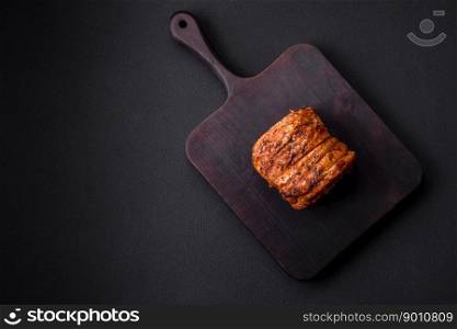 Delicious fresh smoked meat or ham with spices and herbs on a dark concrete background