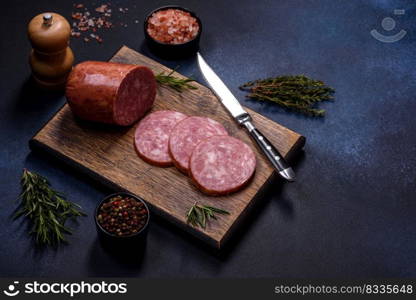 Delicious fresh smoked sausage cut with slices on a wooden cutting board against a dark concrete background. Delicious fresh smoked sausage cut with slices on a wooden cutting board