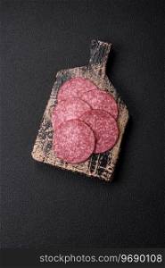 Delicious fresh smoked sausage with salt and spices cut into slices on a dark concrete background