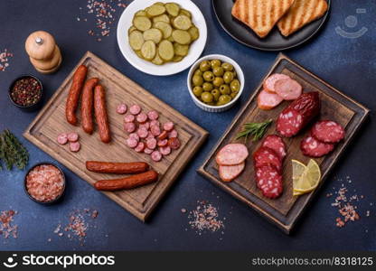 Delicious fresh smoked sausages cut with slices on a wooden cutting board against a dark concrete background. Delicious fresh smoked sausages cut with slices on a wooden cutting board