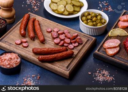 Delicious fresh smoked sausages cut with slices on a wooden cutting board against a dark concrete background. Delicious fresh smoked sausages cut with slices on a wooden cutting board