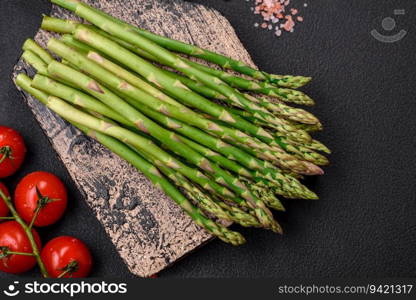 Delicious fresh sprigs of asparagus on a dark textured background. Ingredients for a healthy vegetarian meal