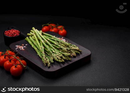 Delicious fresh sprigs of asparagus on a dark textured background. Ingredients for a healthy vegetarian meal