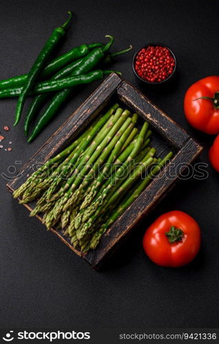 Delicious fresh sprigs of asparagus on a dark textured background. Ingredients for a healthy vegetarian meal