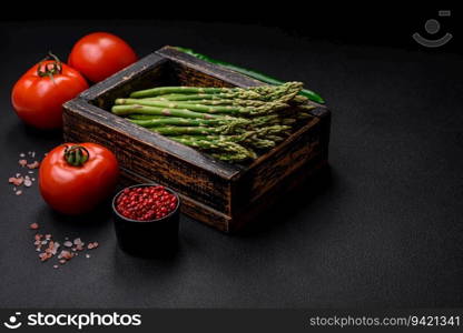 Delicious fresh sprigs of asparagus on a dark textured background. Ingredients for a healthy vegetarian meal