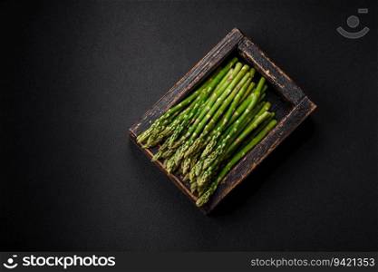 Delicious fresh sprigs of asparagus on a dark textured background. Ingredients for a healthy vegetarian meal