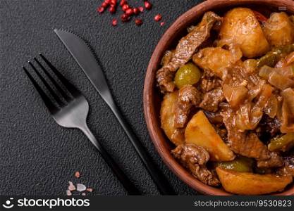 Delicious fresh stew of potatoes, tomatoes, onions, carrots and beef meat with salt, spices and herbs on a dark concrete background