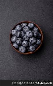 Delicious fresh sweet blueberries in a ceramic bowl on a dark concrete background