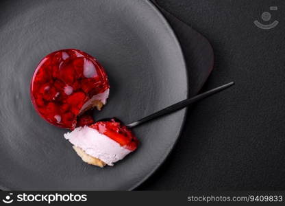 Delicious fresh sweet cheesecake cake with berries and red color jelly on a dark concrete background