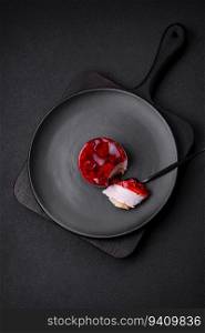 Delicious fresh sweet cheesecake cake with berries and red color jelly on a dark concrete background