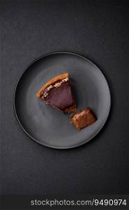 Delicious, fresh, sweet chocolate cake with nuts cut into slices on a dark concrete background