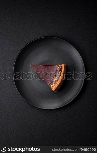 Delicious, fresh, sweet chocolate cake with nuts cut into slices on a dark concrete background