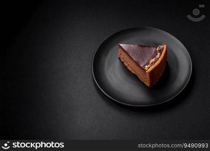 Delicious, fresh, sweet chocolate cake with nuts cut into slices on a dark concrete background