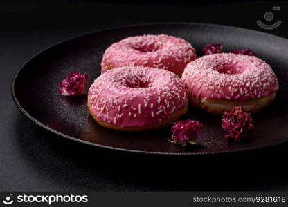 Delicious fresh sweet donuts in pink glaze with strawberry filling on a dark concrete background