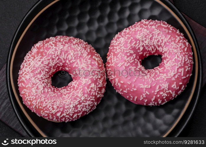 Delicious fresh sweet donuts in pink glaze with strawberry filling on a dark concrete background