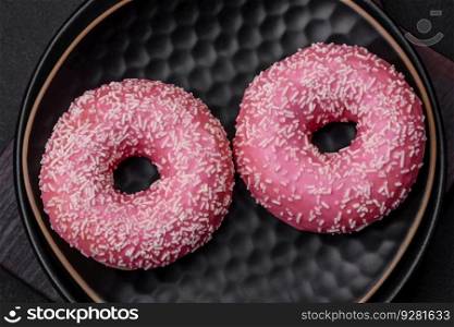 Delicious fresh sweet donuts in pink glaze with strawberry filling on a dark concrete background