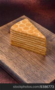Delicious fresh sweet honey cake layer cake with white cream on textured concrete background