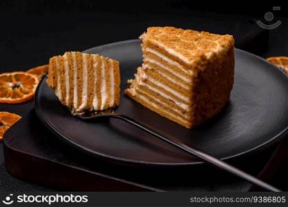 Delicious fresh sweet honey cake layer cake with white cream on textured concrete background
