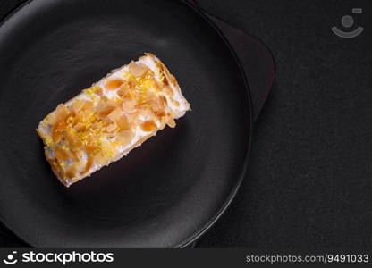 Delicious, fresh, sweet meringue roll with cream, almond chips, nuts and berries cut into slices on a dark concrete background