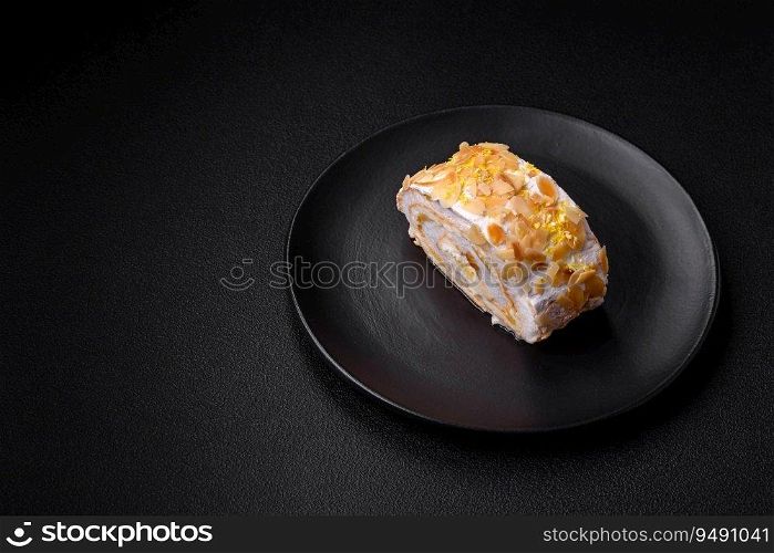 Delicious, fresh, sweet meringue roll with cream, almond chips, nuts and berries cut into slices on a dark concrete background