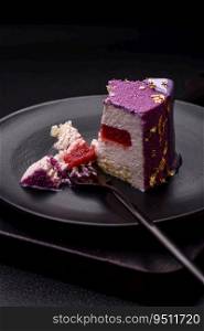 Delicious fresh sweet mousse cake with berry filling topped with pink velvet topping on dark concrete background