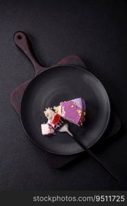 Delicious fresh sweet mousse cake with berry filling topped with pink velvet topping on dark concrete background