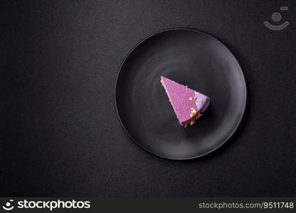 Delicious fresh sweet mousse cake with berry filling topped with pink velvet topping on dark concrete background