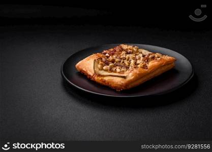 Delicious fresh sweet pie or pizza with pear, brie cheese, honey and nuts on a dark concrete background