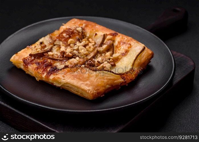 Delicious fresh sweet pie or pizza with pear, brie cheese, honey and nuts on a dark concrete background