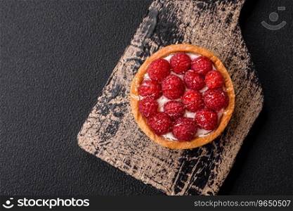 Delicious fresh sweet round tart with ripe raspberries and cream on a dark concrete background