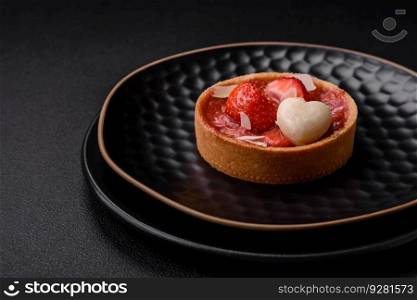 Delicious fresh sweet tartlets with strawberries and coconut flakes on a dark concrete background