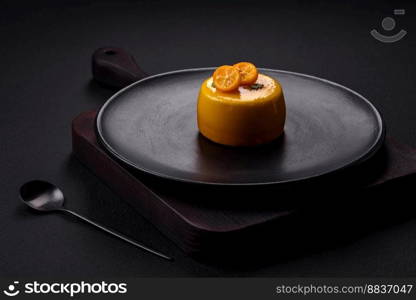 Delicious fresh tartlet with citrus filling and decorated with passion fruit on a black plate