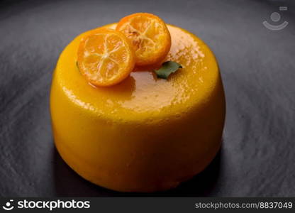 Delicious fresh tartlet with citrus filling and decorated with passion fruit on a black plate