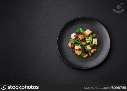 Delicious fresh vegan salad with pear, brie cheese, nuts and grains, and arugula on a ceramic plate on a dark background