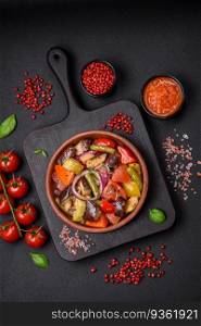 Delicious fresh vegetarian salad with tomatoes, green beans, eggplant, pepper, salt, spices and herbs on a dark concrete background. Delicious fresh vegetarian salad with tomatoes, green beans, eggplant and pepper