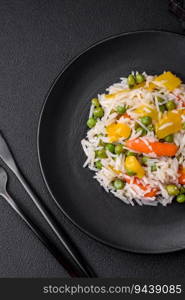 Delicious fresh white boiled rice with vegetables carrots, peppers and asparagus beans on a ceramic plate on a dark concrete background