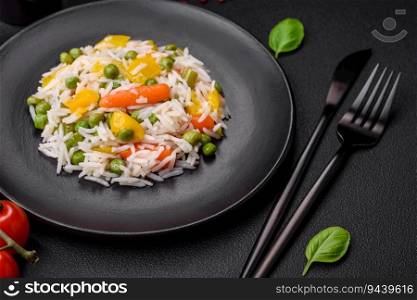 Delicious fresh white boiled rice with vegetables carrots, peppers and asparagus beans on a ceramic plate on a dark concrete background