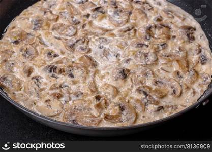 Delicious fresh young ch&ignons sliced into slices in creamy sauce simmered in a black pan. Delicious fresh young ch&ignons sliced into slices in creamy sauce