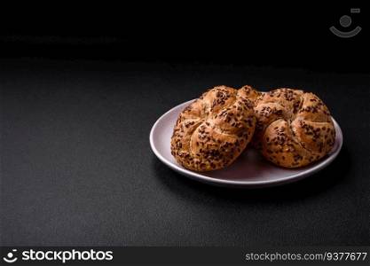 Delicious freshly baked crispy bun or kaiser roll with sesame seeds on dark concrete background