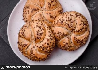 Delicious freshly baked crispy bun or kaiser roll with sesame seeds on dark concrete background
