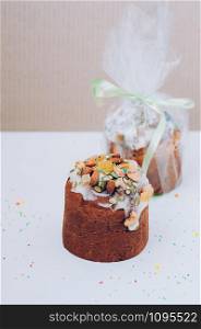Delicious freshly baked Easter cakes with icing, nuts, seeds, candied fruit, multicolored sweet sprinkles, served and packed. Easter, birthday greeting card or web banner concept. Selective focus