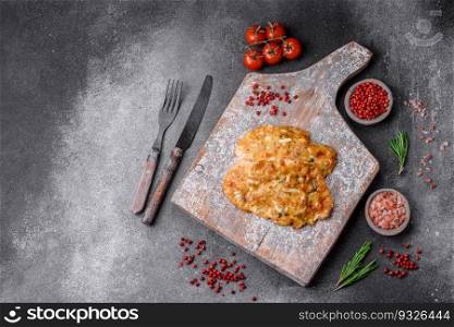 Delicious fried chicken breast in batter with mustard, salt, spices and cheese on a dark concrete background